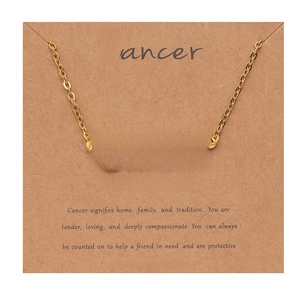 Detail of 18k gold plated Cancer zodiac necklace displayed on a Kraft paper card