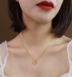Close-up of minimalist 18k gold heart pendant necklace on model with smooth metallic finish