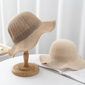 Detail view of hollow knitted sun hat featuring elegant wavy brim and refined texture