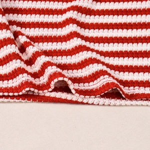 Gros plan détaillé du tissu en maille rayé rouge et blanc montrant la texture douce