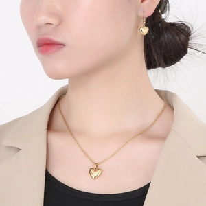 Gros plan d'une femme portant l'ensemble collier et boucles d'oreilles cœur doré