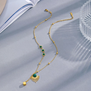 Elegant gold fan pendant necklace with green malachite stones on textured fabric