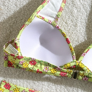 Vue détaillée du haut de bikini à fleurs avec coussinets intérieurs blancs et fermoir métal