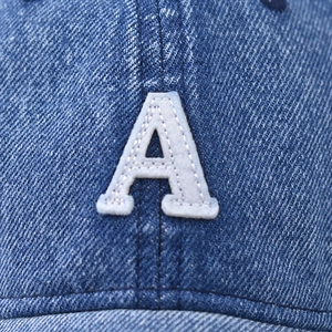 Primo piano della lettera A ricamata su un cappellino da baseball in denim blu lavato