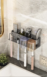Detail of grey wall-mounted toothbrush holder with cups and organizer shelf