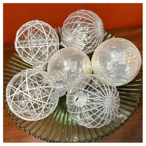 Detail of six varied texture champagne Christmas baubles in a green glass bowl