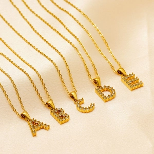 Close-up of gold-plated initial pendants with white zircon inlay on soft silk