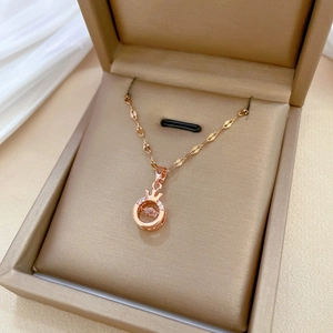 Elegant rose gold crown necklace with sparkling crystals in a beige jewelry box
