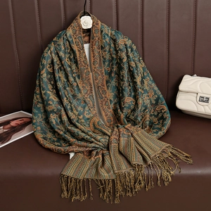 Close-up of green cashmere scarf with paisley pattern and fringes on leather sofa