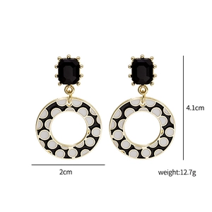 Close-up of geometric earrings with black rectangular gems and polka dot round pendants