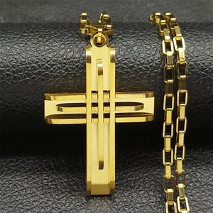 Vue détaillée du pendentif croix multicouche en acier doré sur un fond en cuir noir