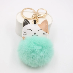 Close-up of mint green pompom keychain featuring a cute lucky cat face and golden clasp