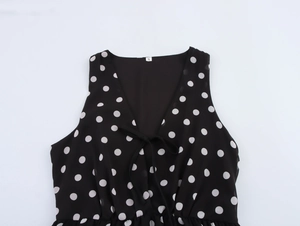 Détail du col en V avec nœud papillon et motif à pois sur une robe sans manches élégante
