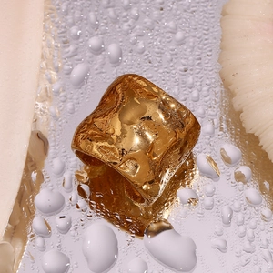 Vista macro di anello largo placcato oro 18K con trama lavica e gocce d'acqua lucide