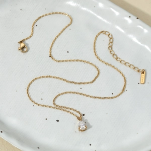 Detail of gold stainless steel necklace with teardrop crystal on ceramic plate