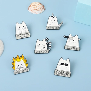 Macro detail of six cartoon cat enamel pins featuring humorous quotes on a blue surface