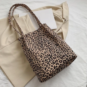 Detailed close-up of a leopard print canvas tote bag with brown handles on light fabric
