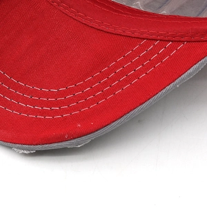 Macro detail of red cotton baseball cap brim with grey distressed edges and triple stitching
