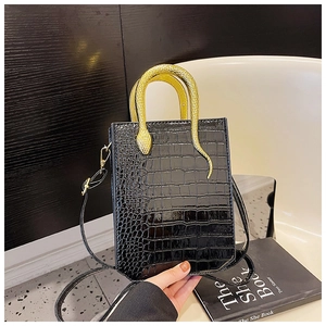 Detailed close-up of a black faux crocodile leather bag with a gold snake-shaped metal handle
