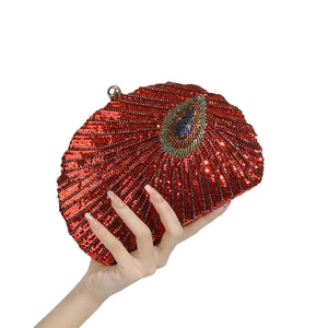 Detailed view of red sequin evening bag with beaded peacock pattern held by hand