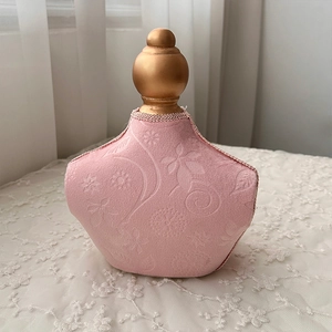Detailed view of pink fabric jewelry display stand with embossed pattern and gold finial