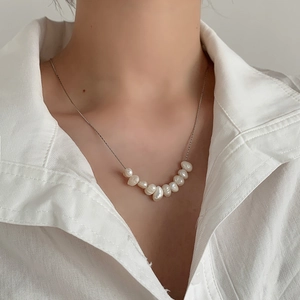 Close-up of minimalist natural freshwater pearl necklace on neck with silver chain