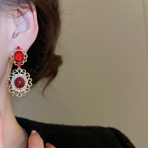 Close-up of vintage oval red gemstone earrings with sparkling crystal accents on a model