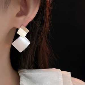 Detail of geometric rhombus earrings with gold plating and silver brushed texture
