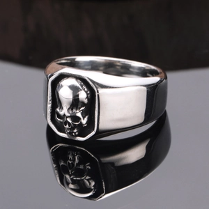 Gothic punk rock silver skull ring for men in polished titanium steel on a black mirror