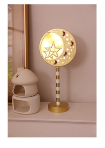 Close-up of golden moon and star LED lamp with warm yellow light and metallic finish