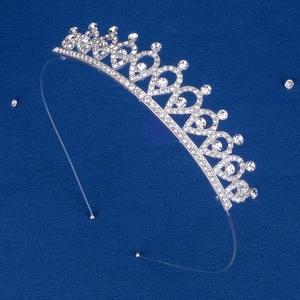 Dettaglio del cerchietto a corona in argento con strass scintillanti su tessuto blu