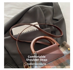 Detail of plaid wool handbag with brown leather trim styled over a dark grey blazer