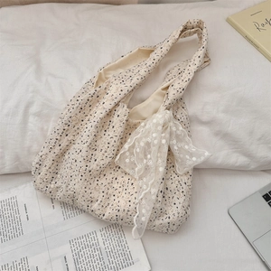 Close-up of cream floral lace handbag with bow decoration in a lifestyle setting
