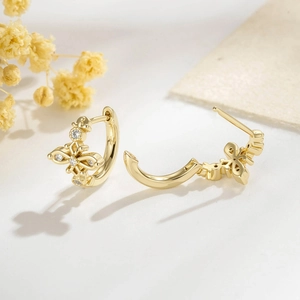 Elegant gold-plated cross hoop earrings with sparkling zircon accents on white surface