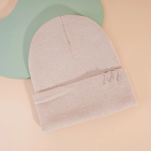 Gros plan du bonnet en tricot rose avec trois anneaux en métal argenté sur le revers