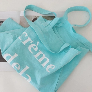 Flache Ansicht der minzgrünen Canvas-Tasche mit weißer Aufschrift auf Modemagazin