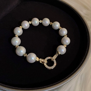 Macro detail of large iridescent pearl bracelet with gold-plated rhinestone encrusted clasp