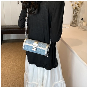 Detail of blue glitter cylindrical crossbody bag with silver leather trim and chain strap