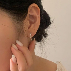 Close-up of minimalist S925 sterling silver bow earrings on model ear with metallic luster