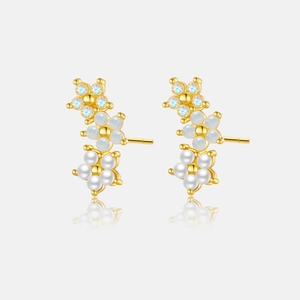 Detail of flower earrings with gold finish, white pearls, and iridescent zircons