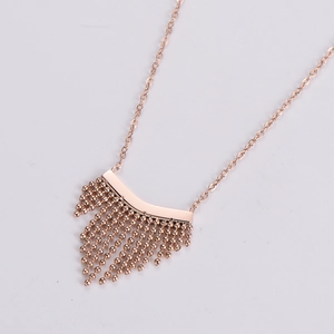 Close-up of rose gold bohemian fan tassel necklace with polished beads and curved pendant