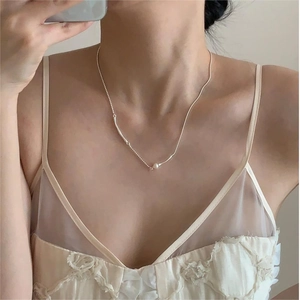 Minimalist silver necklace with a single pearl pendant worn on the collarbone of a model