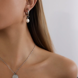 Elegant stainless steel silver pearl earrings and matching embossed coin necklace on model