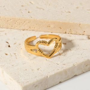 Minimalist gold open heart ring with hollow gesture design on a beige stone background