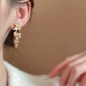 Detail of elegant gold-tone layered irregular metal tassel earrings on model