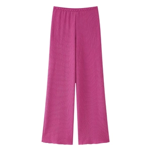 Dettaglio dei pantaloni rosso rosa a vita alta con texture plissettata verticale