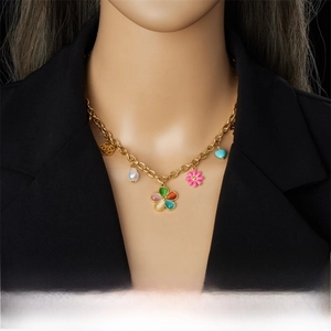 Detail of gold chain necklace with colorful resin flowers and heart charms on a model