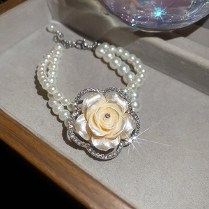 Detailed close-up of double-layer pearl bracelet with resin flower and sparkling diamonds