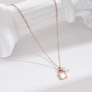 Elegant rose gold necklace with white shell lock pendant and pearl on white pillar