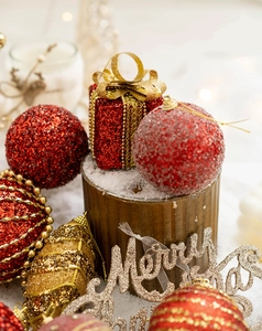 Close-up of golden Merry Christmas sign with red and gold glitter ball ornaments